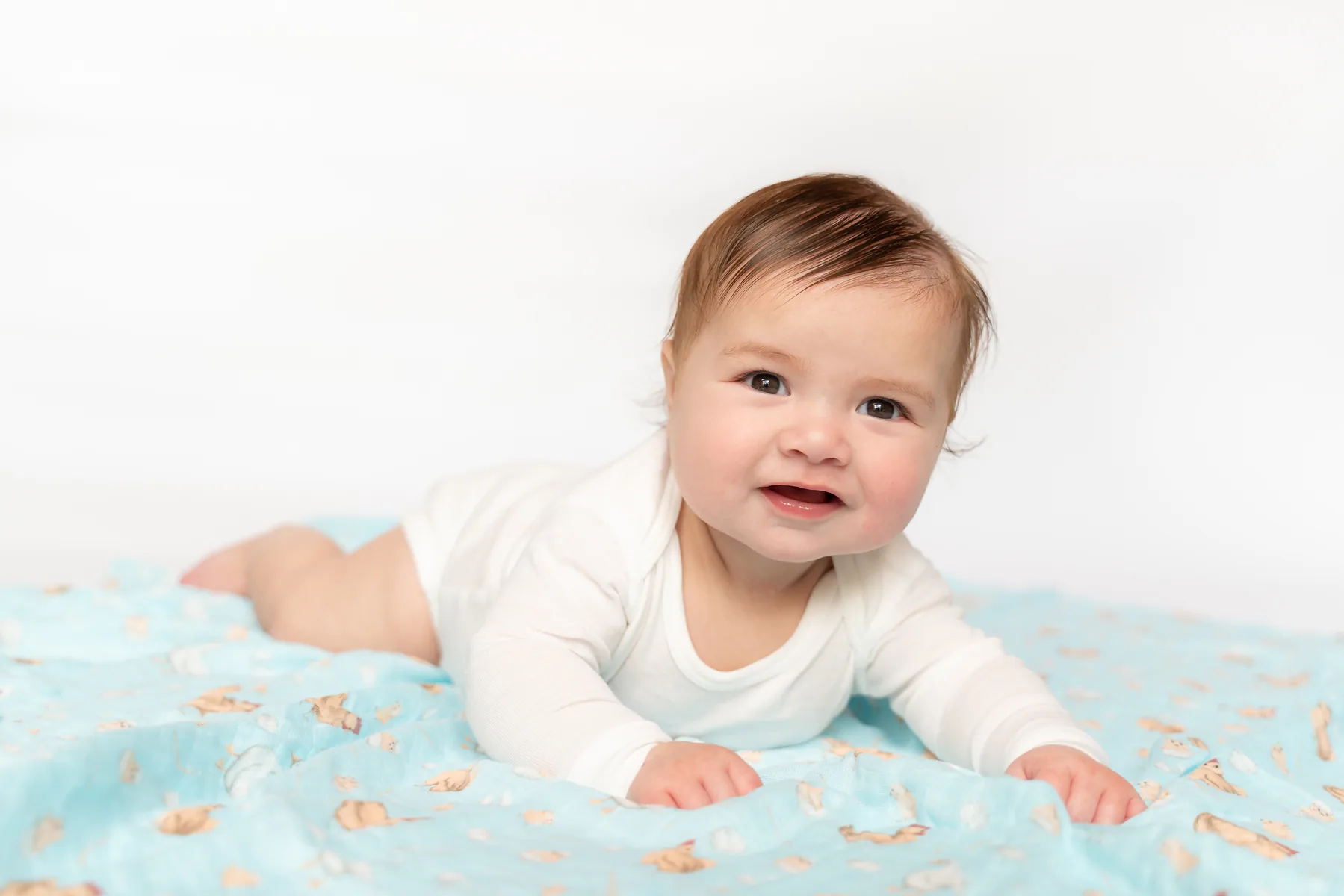 Baby lying on a soft blue Mama Cookie bamboo muslin swaddle blanket